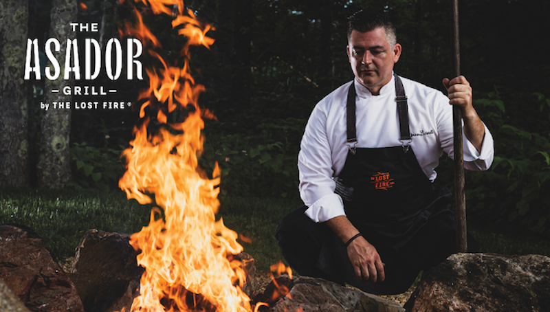 Asador Grill with chef standing near fire